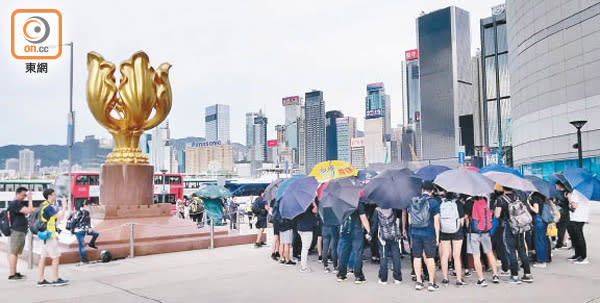 一批示威者走到金紫荊廣場，在地上噴上「光復香港、時代革命」字句。（溫國佳攝）