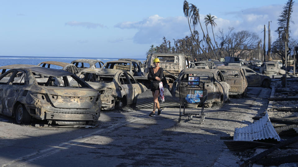 Une mujer camina entre los restos de vehículos consumidos por el fuego, el viernes 11 de agosto de 2023, en Lahaina, Hawai. (AP Foto/Rick Bowmer)