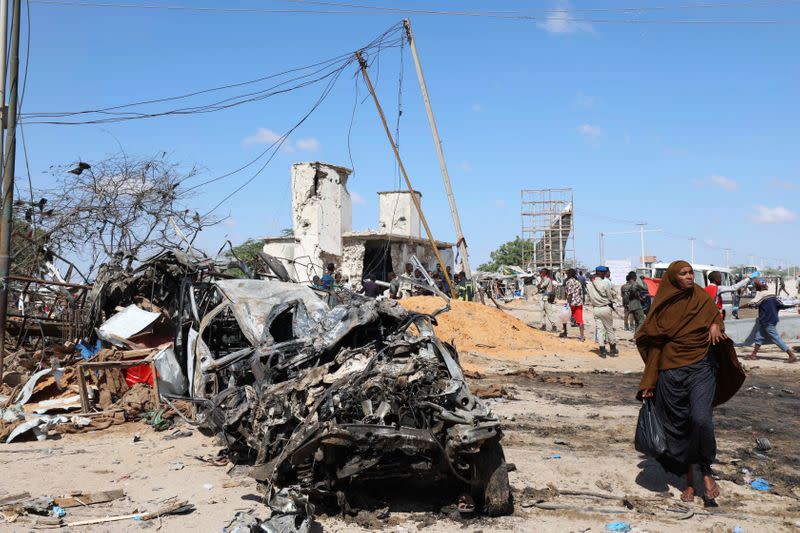 A Somali woman walks past a wreckage at the scene of a car bomb explosion at a checkpoint in Mogadishu