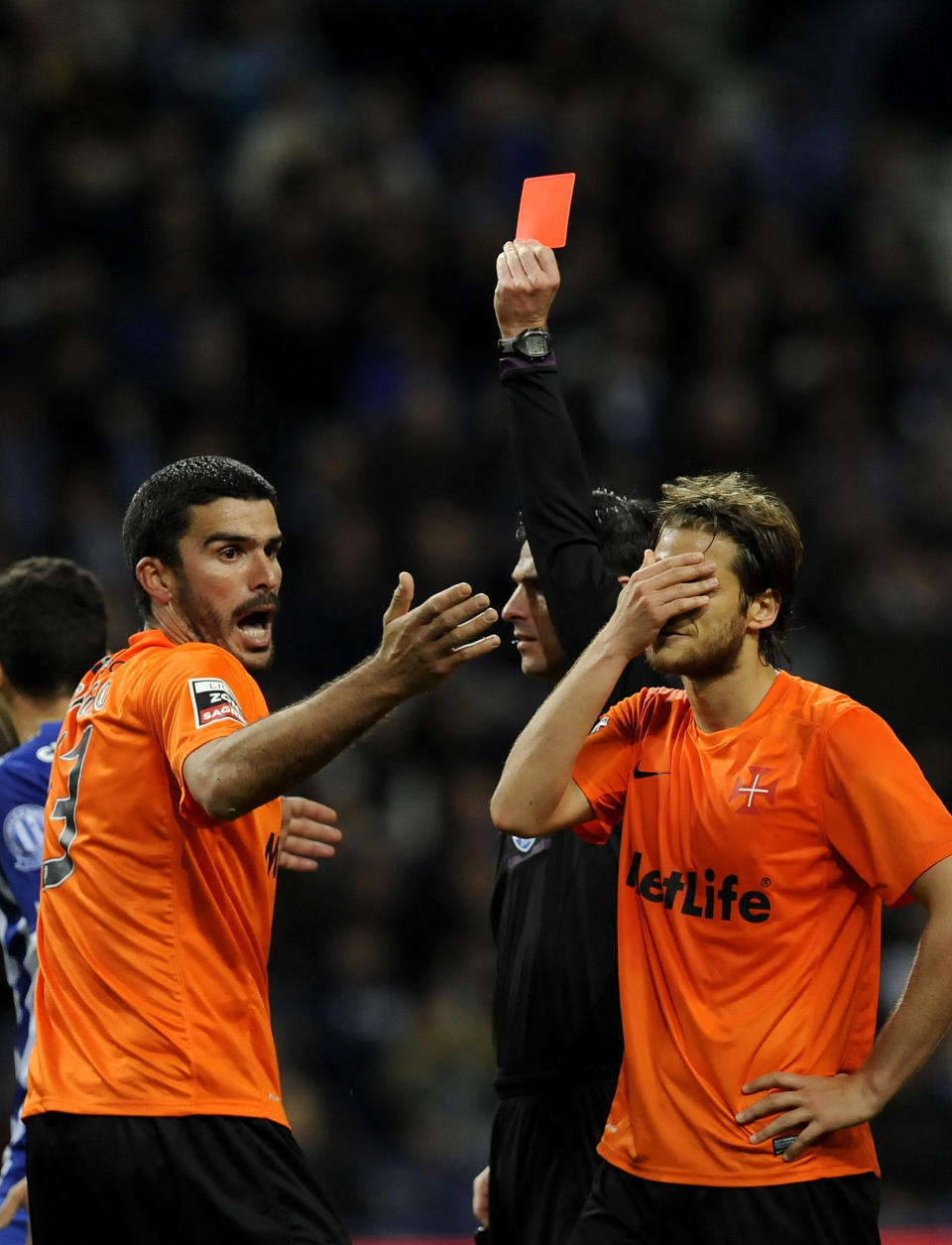 Belenenses' Joao Afonso, left, is shown a red card by referee Carlos Xistra, with Joao Meira at right, in a Portuguese League soccer match with FC Porto at the Dragao stadium in Porto, Portugal, Sunday, March 23, 2014. Porto won 1-0.(AP Photo/Paulo Duarte)
