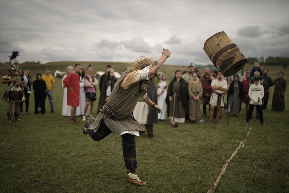 A participant in the Romula Fest historic reenactment event throws a log in an ancient sports competition in the village of Resca, Romania, Saturday, Sept. 3, 2022. (AP Photo/Andreea Alexandru)