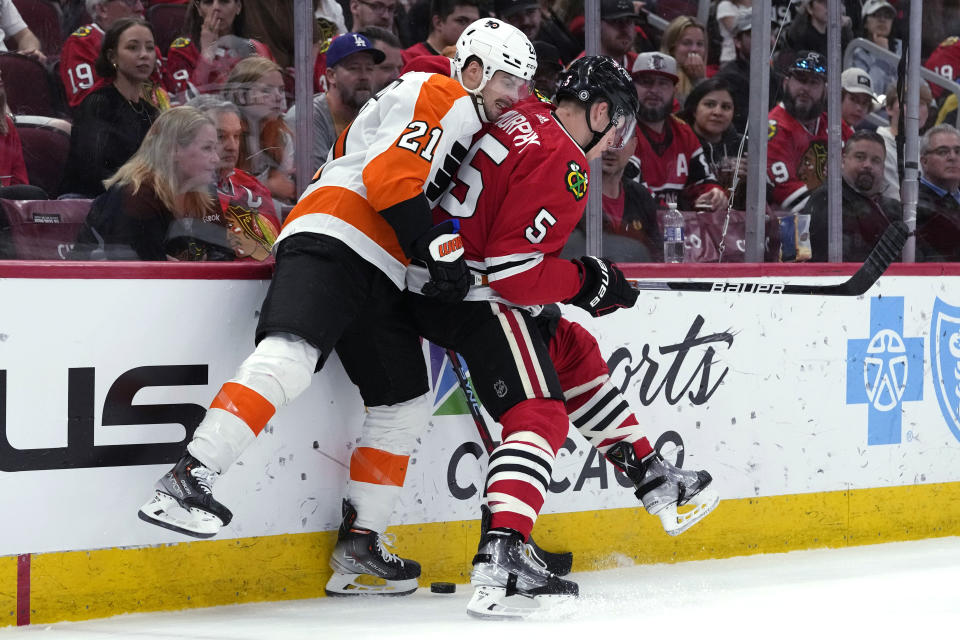 Philadelphia Flyers center Scott Laughton, left, and Chicago Blackhawks defenseman Connor Murphy vie for the puck during the first period of an NHL hockey game in Chicago, Thursday, April 13, 2023. (AP Photo/Nam Y. Huh)