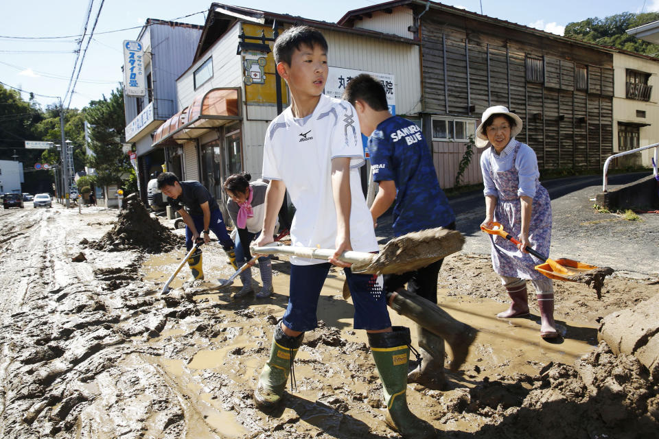 Students and residents scoop dirt as the town is flooded Typhoon Hagibis, in Marumori, Miyagi prefecture, northern Japan, Sunday, Oct. 13, 2019. Rescue efforts for people stranded in flooded areas are in full force after a powerful typhoon dashed heavy rainfall and winds through a widespread area of Japan, including Tokyo.(Kyodo News via AP)