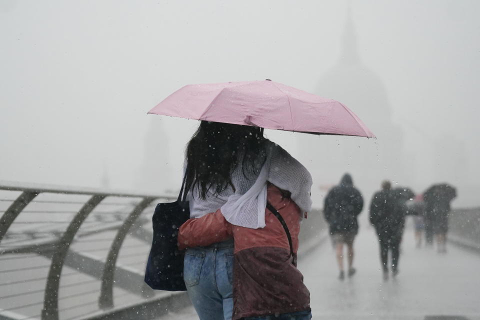 People with umbrellas walking in the rain on Millennium Bridge, London, Wednesday Aug. 17, 2022.. After weeks of sweltering weather, which has caused drought and left land parched, the Met Office's yellow thunderstorm warning forecasts torrential rain and thunderstorms that could hit parts England and Wales. (Victoria Jones/PA via AP)