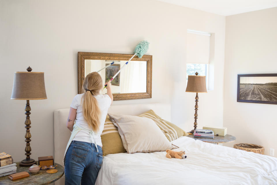 woman dusting bedroom