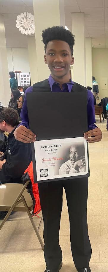 Jeriah Martin holds up his 2024 award for the Martin Luther King Jr. Essay Contest.