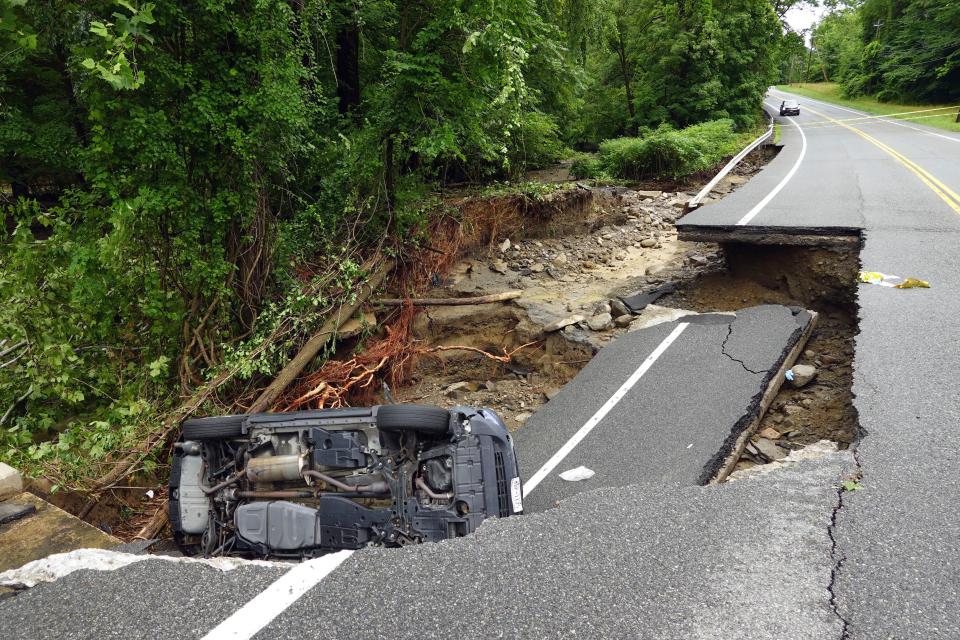 A damaged car lays on part of a collapsed roadway along Route 32 in the Hudson Valley near Cornwall, N.Y., Monday, July 10, 2023. Heavy rain has washed out roads and forced evacuations in the Northeast as more downpours were forecast throughout the day. (AP Photo/Paul Kazdan)