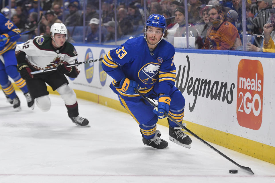 Buffalo Sabres center Ryan Johnson, right, skates the puck away from Arizona Coyotes center Logan Cooley during the first period of an NHL hockey game in Buffalo, N.Y., Monday, Dec. 11, 2023. (AP Photo/Adrian Kraus)