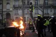 A demonstrator stands on a stepladder during clashes Saturday, Dec. 8, 2018 in Paris. Crowds of yellow-vested protesters angry at President Emmanuel Macron and France's high taxes tried to converge on the presidential palace Saturday, some scuffling with police firing tear gas, amid exceptional security measures aimed at preventing a repeat of last week's rioting. (AP Photo/Rafael Yaghobzadeh)