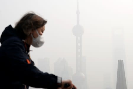 People walk on a bridge in front of the financial district of Pudong during a polluted day in Shanghai