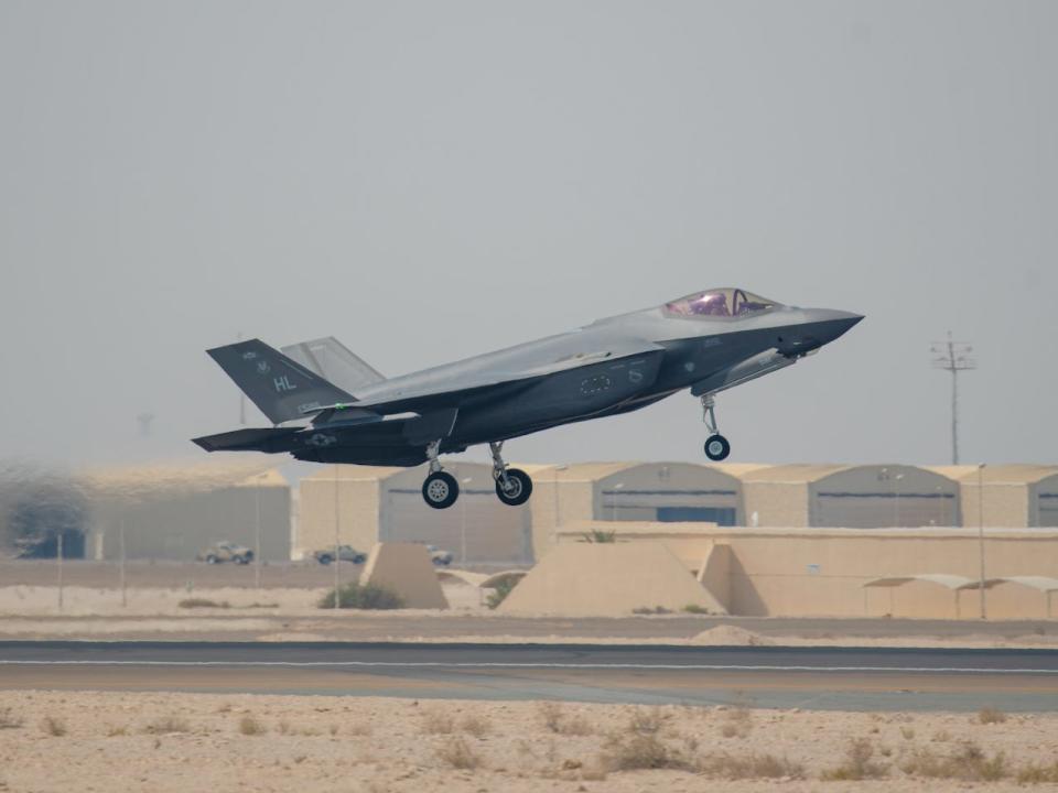 An Air Force F-35A taking off from a sandy-looking airstrip with its landing gear down.