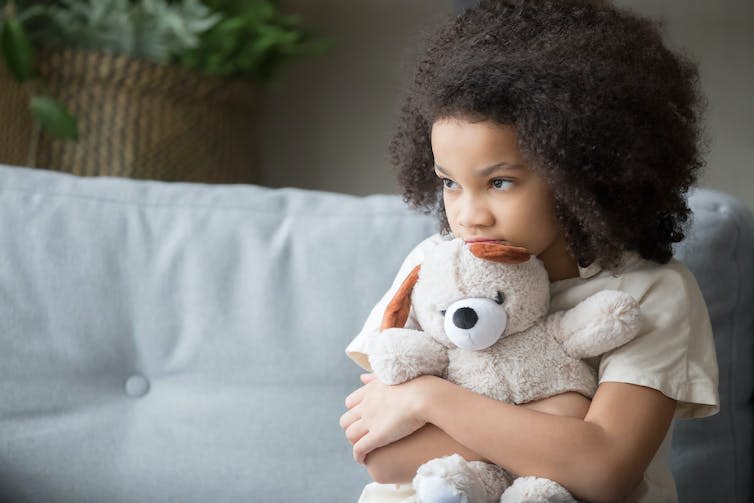 A little girl hugs a teddy.