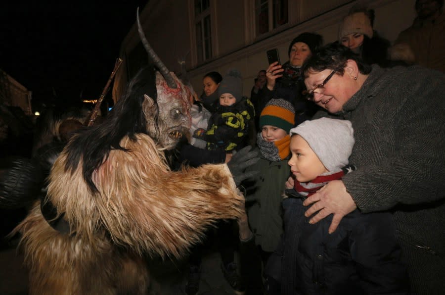 A Krampus scares spectators during a traditional Krampus run in which men and women dress up as pagan Krampus figures to scare people in Hollabrunn, Austria, Saturday, Nov. 30, 2019. (AP Photo/Ronald Zak)