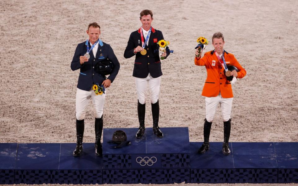 Ben Maher poses with his gold medal on the podium - GETTY IMAGES