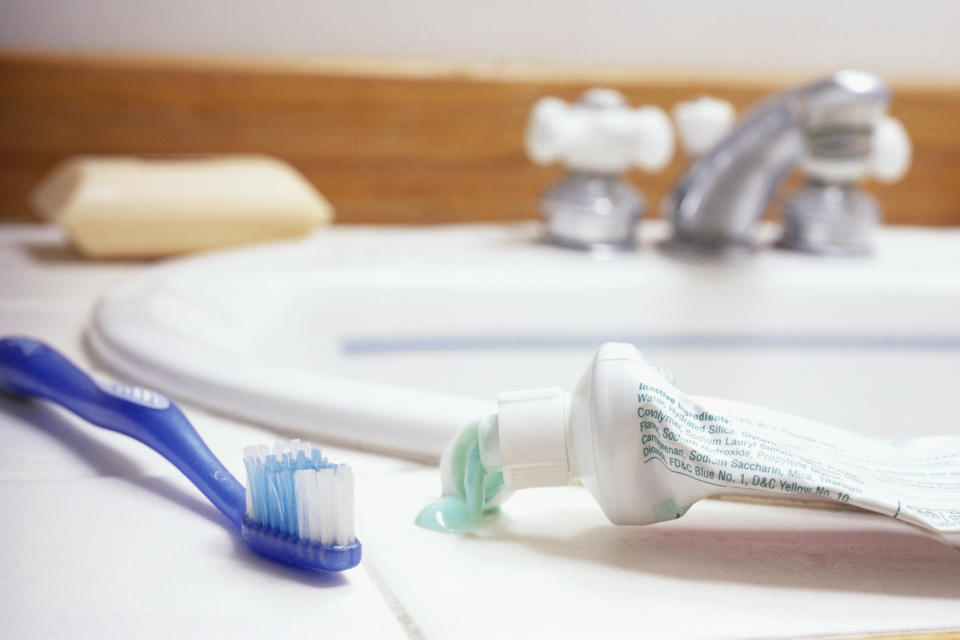 Toothbrush and open toothpaste tube on a bathroom counter