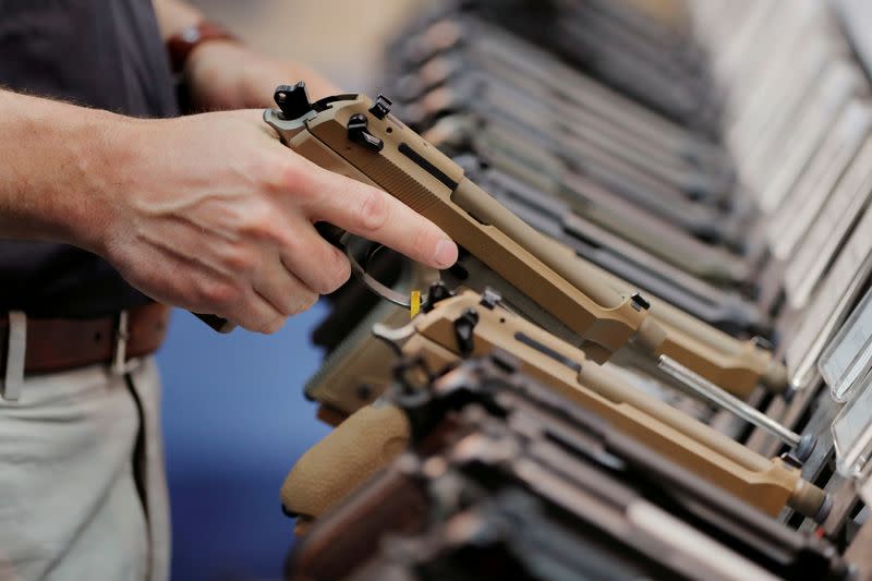 FILE PHOTO: A man inspects a handgun inside of the Beretta booth during the National Rifle Association (NRA) annual meeting in Indianapolis, Indiana