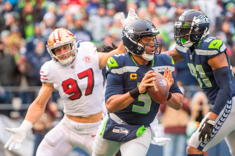 Seattle Seahawks quarterback Russell Wilson (3) scrambles away from San Francisco 49ers defensive end Nick Bosa (97) as tight end Gerald Everett (81) blocks during the first quarter of an NFL game on Sunday at Lumen Field in Seattle.