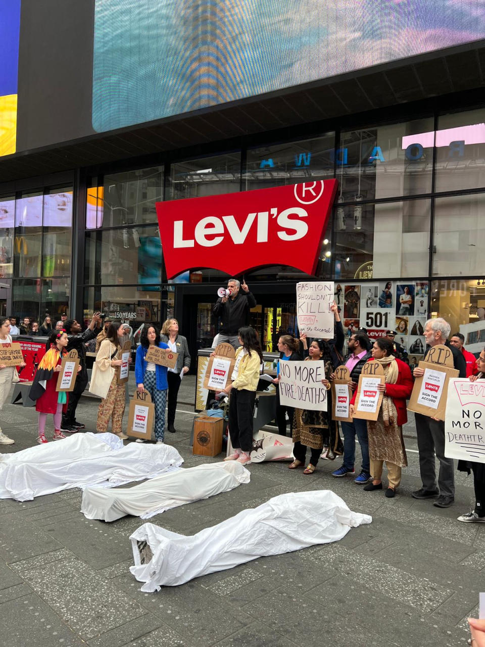 Protestors lay in shrouds to commemorate the four workers who lost their lives at a Levi’s supplier factory in Pakistan in January 2022.