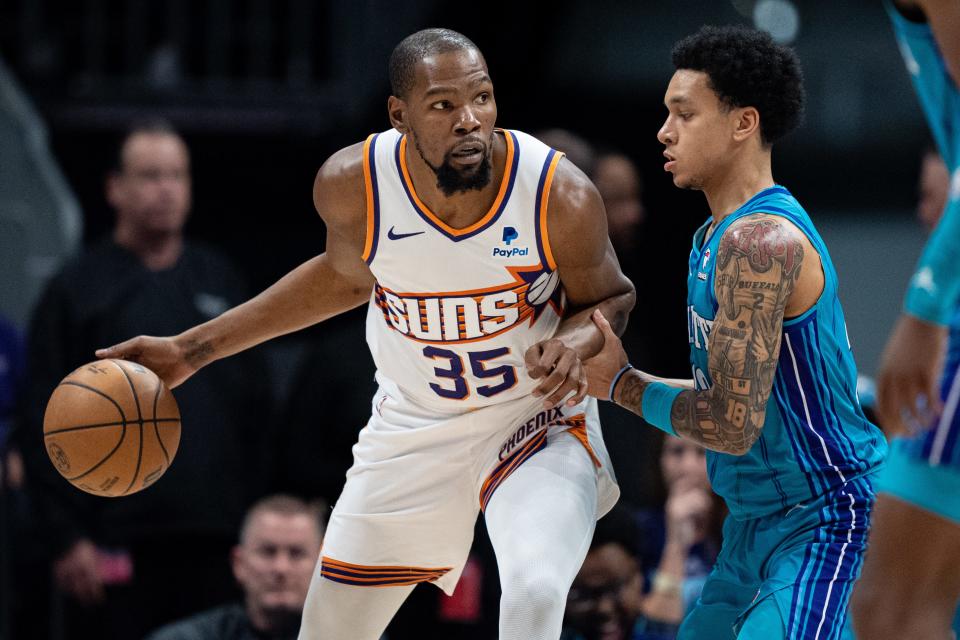 Tre Mann #23 of the Charlotte Hornets guards Kevin Durant #35 of the Phoenix Suns in the first quarter during their game at Spectrum Center on March 15, 2024 in Charlotte.