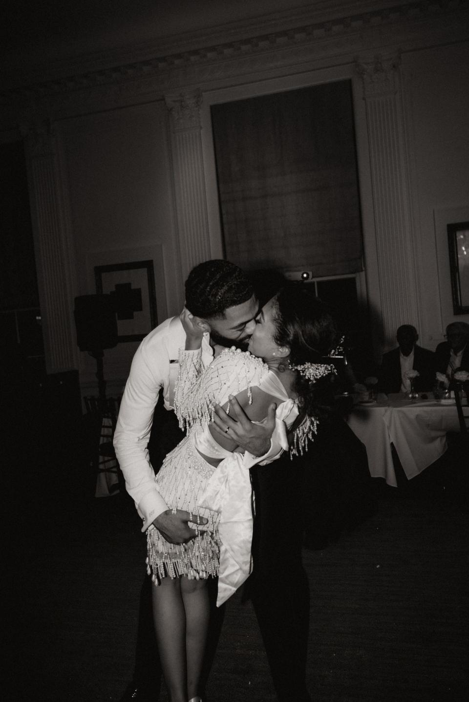A black-and-white phot of a bride and groom kissing.
