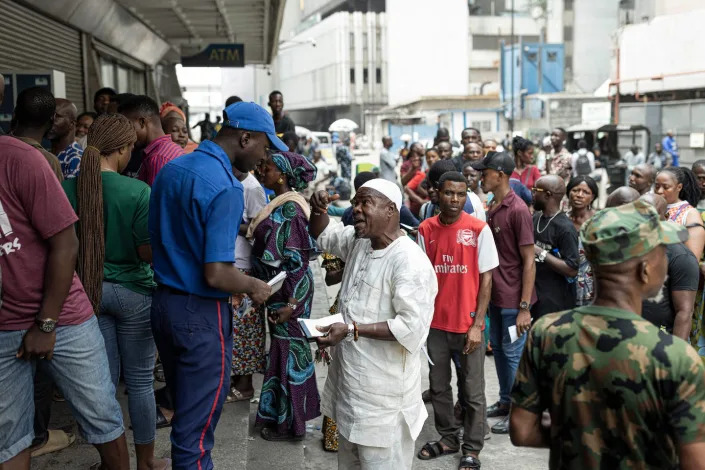 People queue outside a bank in Lagos on February 22, 2023. Nigeria was hit with a scarcity of cash after the central bank began to swap old Naira notes for new bills. Patrick Meinhardt / AFP