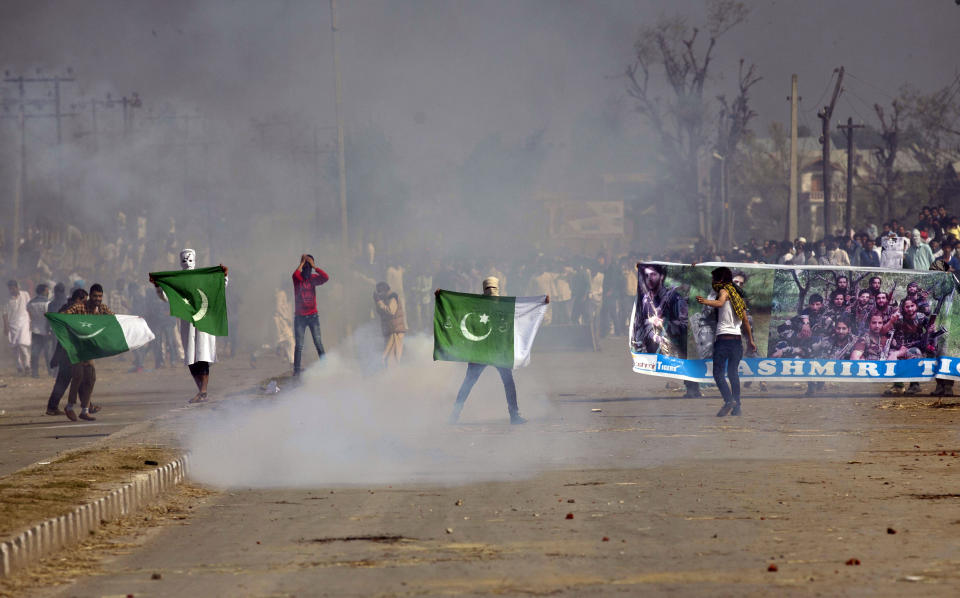 FILE - In this Sept. 25, 2015,file photo, masked Kashmiris hold a national flag of Pakistan and a banner displaying militant leaders of the Hizb-ul Mujahedeen during a protest outside Eidgha, a prayer ground, in Srinagar, Indian controlled Kashmir. India's leaders are anxiously watching the Taliban takeover in Afghanistan, fearing that it will benefit their bitter rival Pakistan and feed a long-simmering insurgency in the disputed region of Kashmir, where militants already have a foothold. (AP Photo/Dar Yasin, File)
