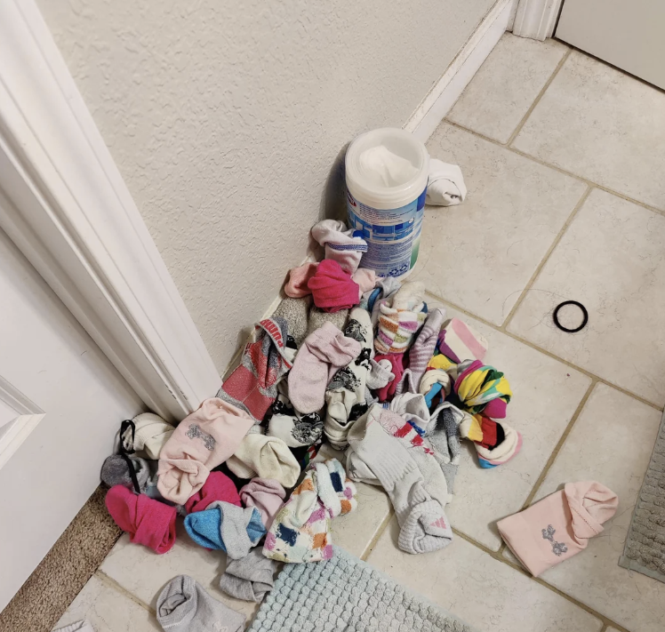 Overflowing pile of various clothes and underwear around a bathroom sink