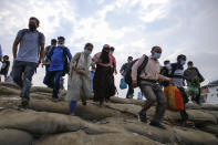 Thousands of people leaving for their native places to celebrate Eid-al-Fitr rush to the Mawa ferry terminal ignoring risks of coronavirus infection in Munshiganj, Bangladesh, Thursday, May 13, 2021. (AP Photo/Mahmud Hossain Opu)