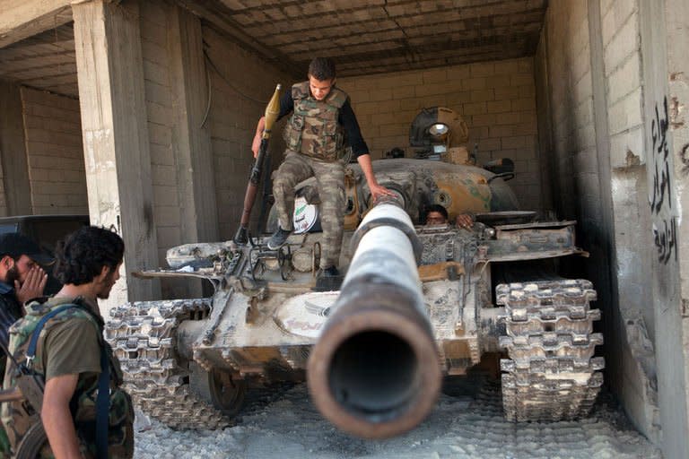 Rebels inspect a T-72 tank parked in a secret location in the northwestern Syrian province of Idlib, on June 22, 2013