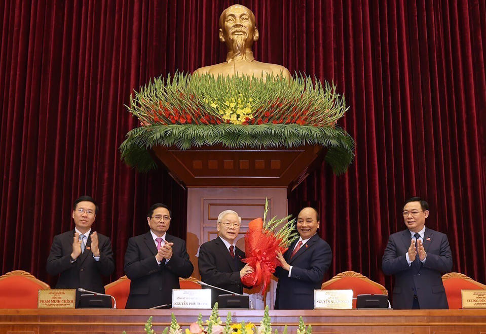 Vietnam Communist party General Secretary Nguyen Phu Trong, center left, is presented with a bouquet by Prime Minister Nguyen Xuan Phuc, center right, in Hanoi, Vietnam, Sunday, Jan. 31, 2021. Vietnam Communist Party has re-elected Nguyen Phu Trong for another term as the party's General Secretary, the country de-facto top leader. Other officials from left; Vo Van Thuong, Secretary of the Central Committee, Pham Minh Chinh, head of the Central Organization Committee and Vuong Dinh Hue, Hanoi Secretary of the Communist Party (Le Tri Dung/VNA via AP)