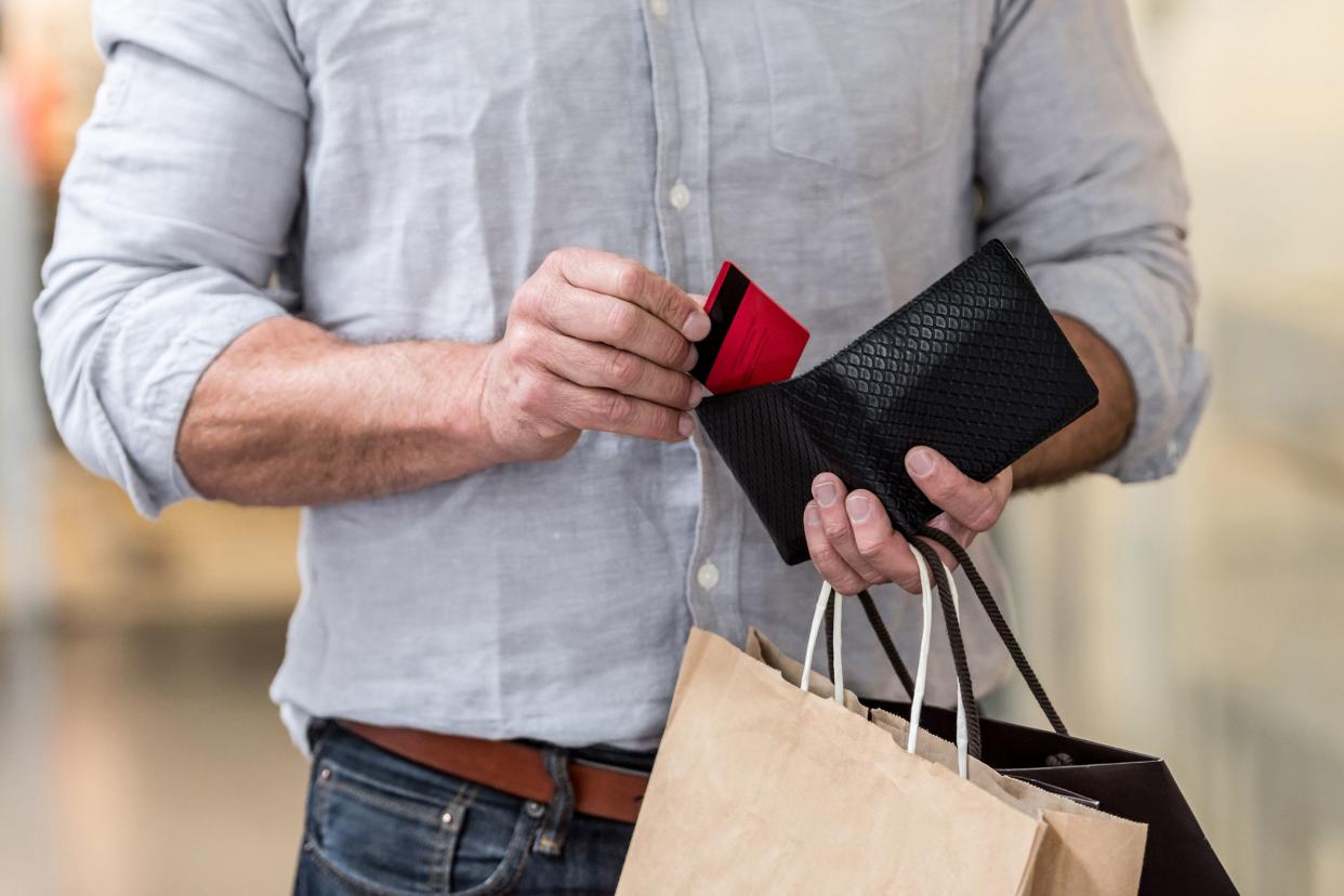 shopping man putting credit card in his wallet