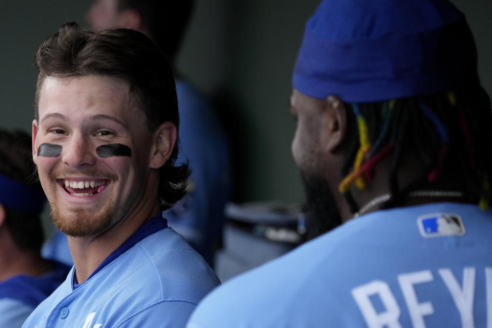 Kansas City Royals' Bobby Witt Jr., left, talks with Franmil Reyes in the dugout after Reyes' three-run home run during the first inning of a spring training baseball game against the Seattle Mariners Sunday, Feb. 26, 2023, in Surprise, Ariz. (AP Photo/Charlie Riedel)