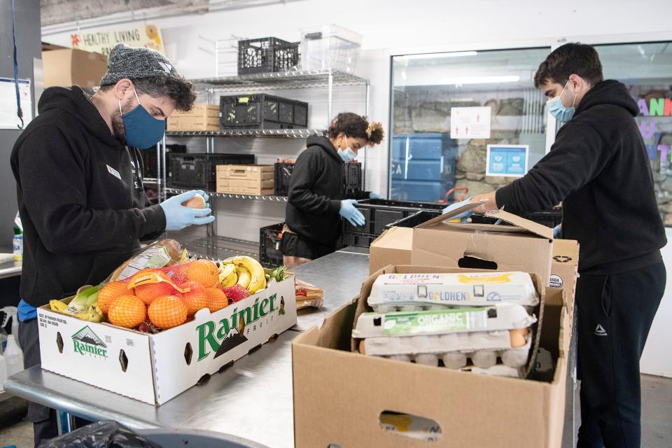 From left, Miguel Hernandez, Tiphereth Hassan and Kyle Patterson sort through donated produce at YMCA in Asheville January 25, 2022.