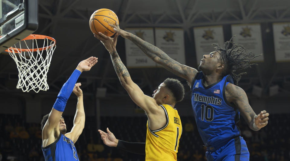 Wichita State's Xavier Bell goes up a for a shot against Memphis defenders Jaykwon Walton, right, and Nicholas Jourdain, left, during the first half of an NCAA college basketball game, Sunday, Jan. 14, 2024, in Wichita, Kan. (Travis Heying/The Wichita Eagle via AP)