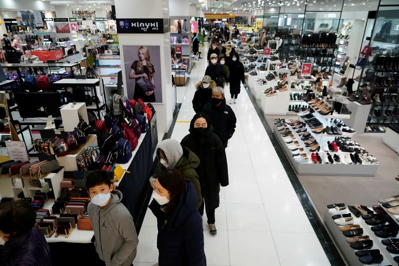 People wearing masks after the coronavirus outbreak wait in a line to buy masks at a department store in Seoul