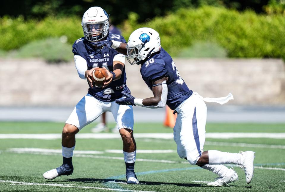 Monmouth quarterback Tony Muskett (11) hands the ball to running back Juwon Farri during the Hawks' 45-15 loss to Holy Cross on Sept. 25, 2021, in West Long Branch.