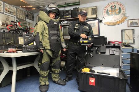 Philippine National Police bomb squad members pose for pictures with a bomb scanner and bomb suit at a police station in Manila September 15, 2014. REUTERS/Romeo Ranoco