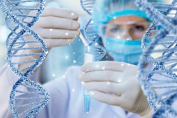 Scientist holding vial and dropping solution into it while being surrounded by DNA modules.