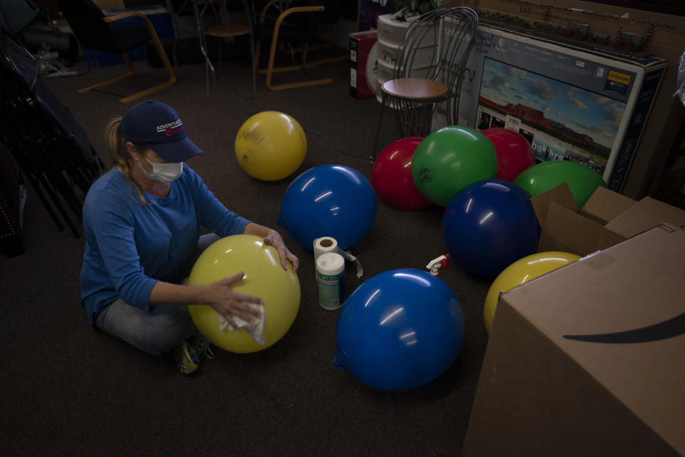 Trina Ansdell, wife of Allan Ansdell Jr, owner and president of Adventure City amusement park, wipes dust off balloons in the office ahead of the park's reopening in Anaheim, Calif., Wednesday, April 14, 2021. The family-run amusement park that had been shut since March last year because of the coronavirus pandemic reopened on April 16. "It has been an emotional roller coaster, especially watching my husband and the family," said the wife. "It was hard to get excited at the beginning that we finally had the green light or that it was soon in the distance because we've been on hold for so long." (AP Photo/Jae C. Hong)