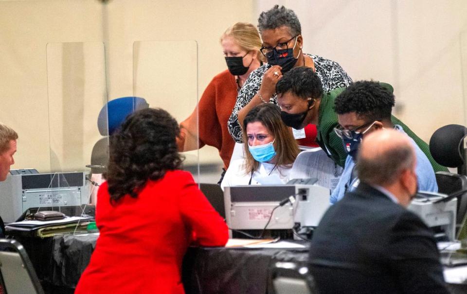 State Board of Elections workers huddle around a computer at the NC State Fairgrounds after a court order Monday temporarily blocked candidates from filing to run in some of the 2022 elections Monday, Dec. 6, 2021.