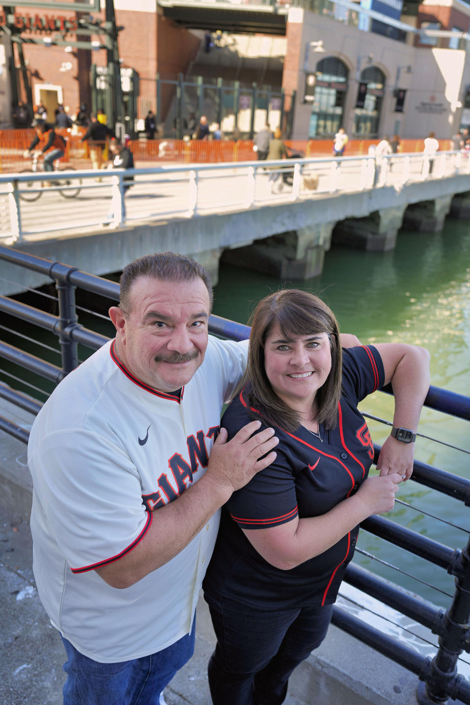 Dan and Tiffany Fuentes, a family that hosted minor league player Tristan Beck, pose for a photo outside Oracle Park before a baseball game between the San Francisco Giants and the New York Mets on Thursday, April 20, 2023, in San Francisco. Giants pitcher Tristan Beck was called up to play his first major league baseball game on April 20. Host family programs were suspended during the coronavirus pandemic over health concerns. When minor league players reached a historic initial collective bargaining agreement with Major League Baseball in March, the league agreed to double salaries and provide guaranteed housing to most players. The use of host families was officially outlawed. (AP Photo/Tony Avelar)