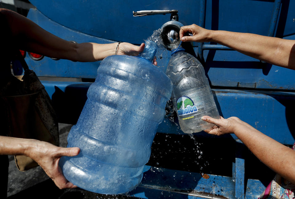 People collect water from a truck that delivers water during rolling blackouts, in Caracas, Venezuela, Tuesday, March 12, 2019. The blackout marked another harsh blow to a country paralyzed by turmoil as the power struggle between Venezuelan President Nicolas Maduro and opposition leader Juan Guaido stretches into its second month and economic hardship grows. (AP Photo/Eduardo Verdugo)