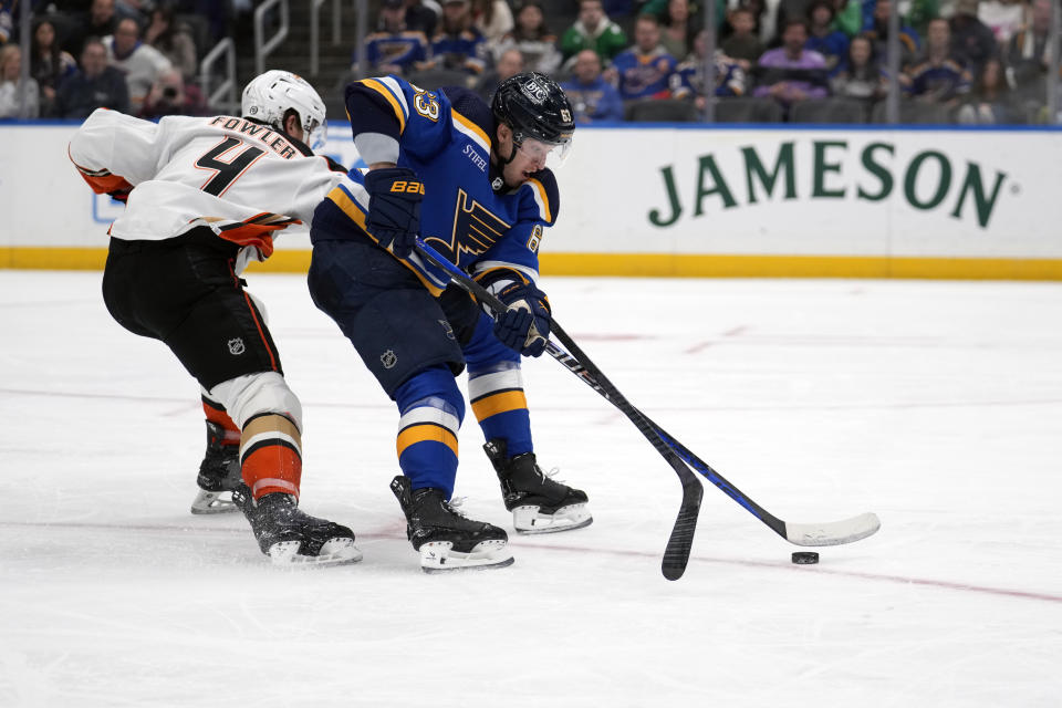 St. Louis Blues' Jake Neighbours (63) chases after a loose puck as Anaheim Ducks' Cam Fowler (4) defends during the second period of an NHL hockey game Sunday, March 17, 2024, in St. Louis. (AP Photo/Jeff Roberson)