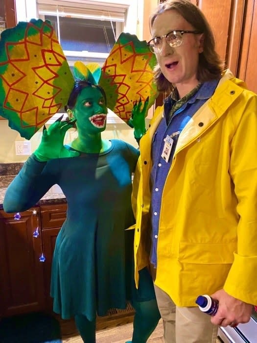 Someone dressed as Dennis Nedry in his iconic yellow jacket, and another person dressed as a Diophosaur, green paint and all