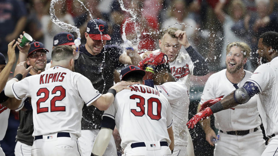 The Cleveland Indians mob Carlos Santana after Santana hit a game-winning solo home run in the ninth inning of a baseball game against the Boston Red Sox, Monday, Aug. 12, 2019, in Cleveland. The Indians won 6-5. (AP Photo/Tony Dejak)