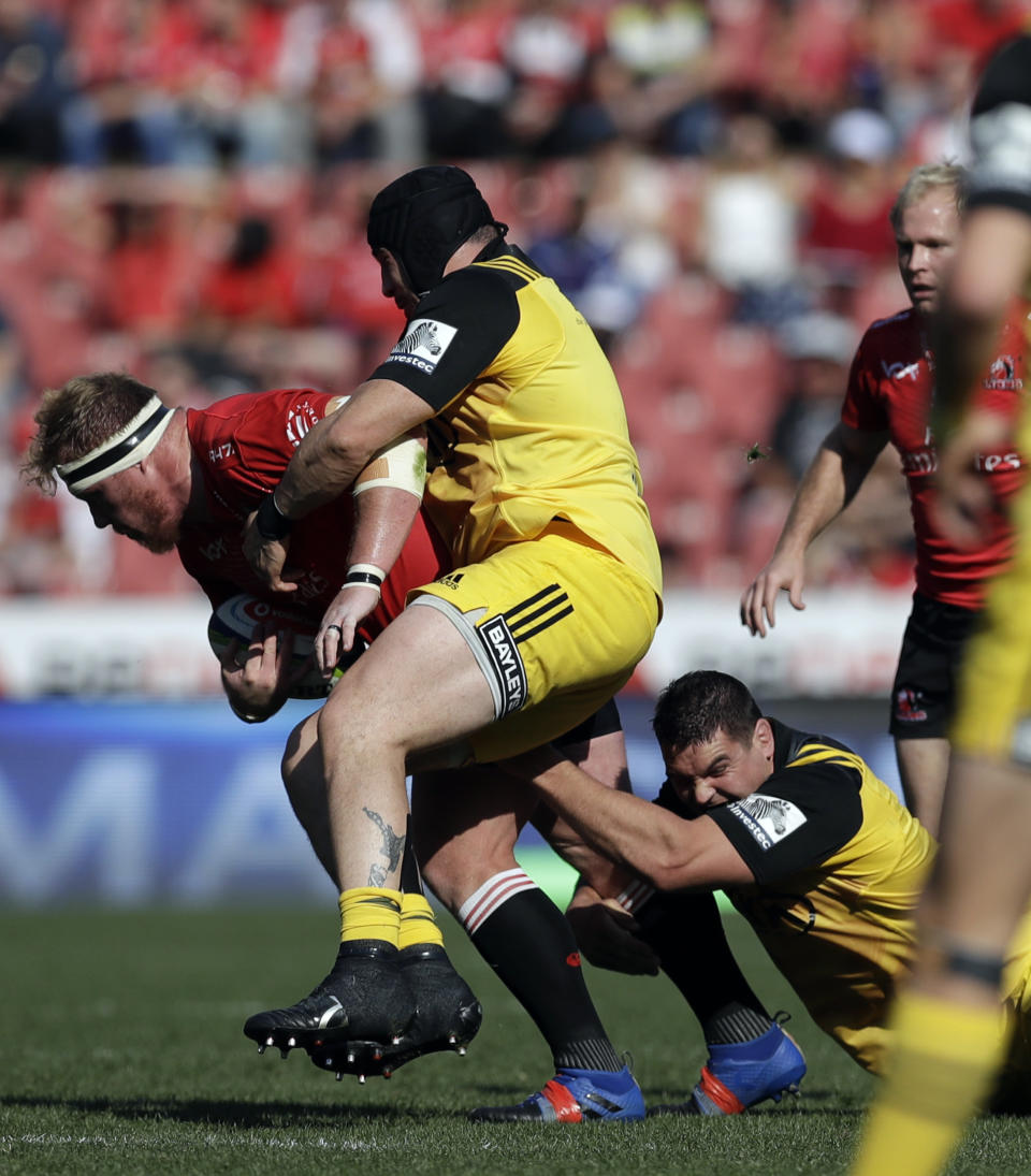 FILE - Lions' Jacques van Rooyen, left, is tackled by Hurricanes' Jeff To'omaga-Allen, middle, during the rugby semifinal match between Lions and Hurricanes, at Ellis Park stadium in Johannesburg, South Africa, on July 29, 2017. A loophole that has allowed rugby players to more easily switch allegiances is helping reshape a sport that has previously tended to tie representative players to one country for life. (AP Photo/Themba Hadebe, File)