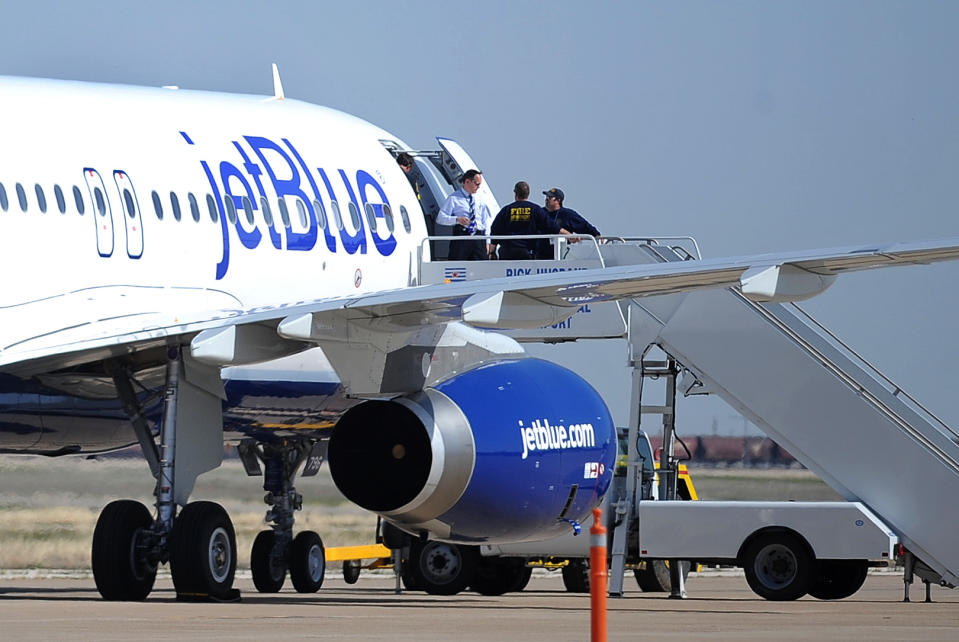 Authorities board JetBlue flight 191, which was headed from New York to Las Vegas, after an emergency landing at Rick Husband Amarillo International Airport in Amarillo, Texas, Tuesday, March 27, 2012, when an unruly pilot caused the Las Vegas-bound flight to be diverted. Passengers said the pilot screamed that Iraq or Afghanistan had planted a bomb on the flight, was locked out of the cockpit, and then tackled and restrained by passengers. The pilot who subsequently took command of the aircraft elected to land in Amarillo at about 10 a.m., JetBlue Airways said in a statement. (AP Photo/The Amarillo Globe News, Roberto Rodriguez)