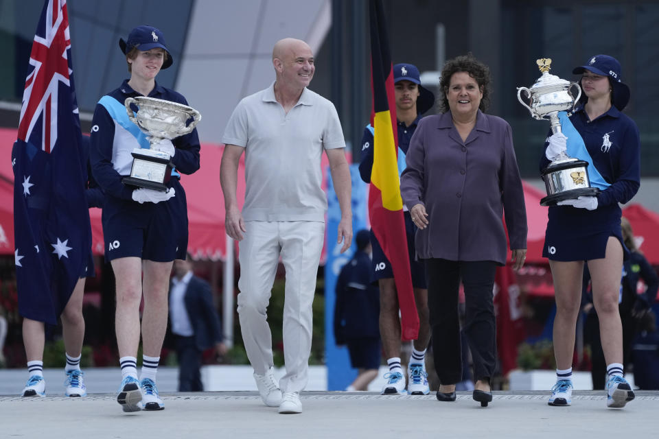 Former Grand Slam champions Andre Agassi and Evonne Goolagong Cawley walk with ball kids carrying the women’s, Daphne Akhurst Memorial Cup and the men’s Norman Brookes Challenge Cup trophies ahead of the start of Australian Open tennis championships at Melbourne Park, Melbourne, Australia, Sunday, Jan. 14, 2024. (AP Photo/Andy Wong)