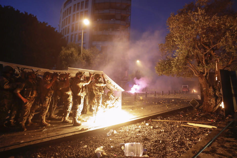 Fuerzas de seguridad se cubren con sus escudos durante un enfrentamiento con manifestantes que protestan contra el gobierno después de la explosión del martes en el puerto de Beirut, el sábado 8 de agosto de 2020 en Beirut. (AP Foto/Hassan Ammar)