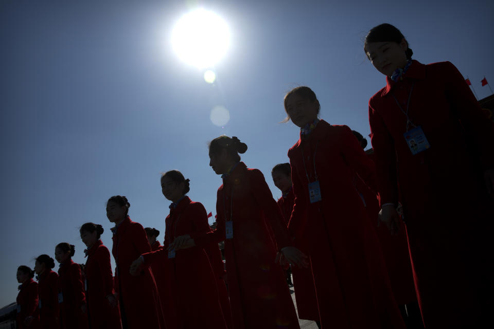 FILE - Hospitality staff are silhouetted by the sun as they pose for a group photo during a plenary session of the Chinese People's Political Consultative Conference (CPPCC) at the Great Hall of the People in Beijing, Thursday, March 9, 2017. (AP Photo/Mark Schiefelbein, File)